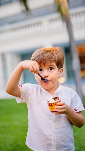 Criança comendo açaí Trevo em copo Trevo durante festa ao ar livre